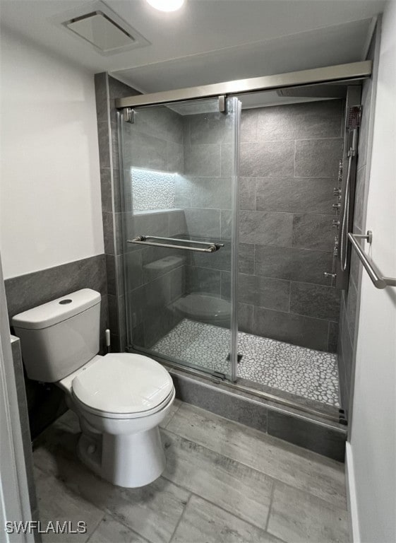 bathroom with toilet and a shower with door