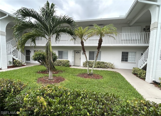 view of front of house featuring a front yard and a balcony