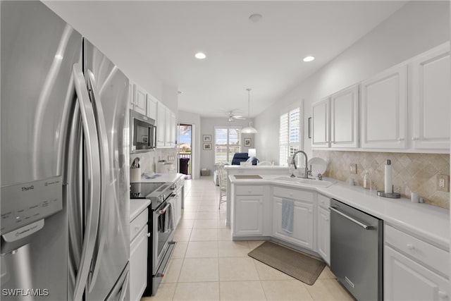 kitchen with appliances with stainless steel finishes, light tile patterned flooring, sink, backsplash, and white cabinetry