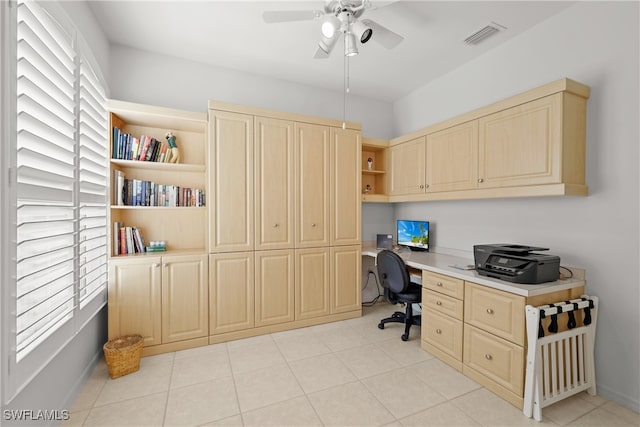 office with built in desk, ceiling fan, and light tile patterned flooring