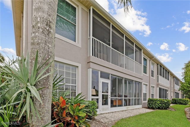 rear view of property with a sunroom and a lawn