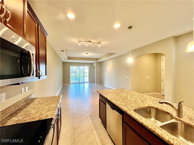 kitchen with a raised ceiling, sink, light stone countertops, decorative light fixtures, and stainless steel appliances