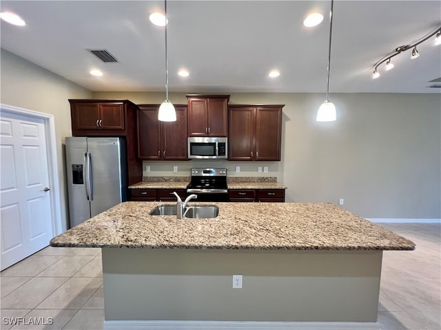 kitchen with a kitchen island with sink, sink, decorative light fixtures, and appliances with stainless steel finishes