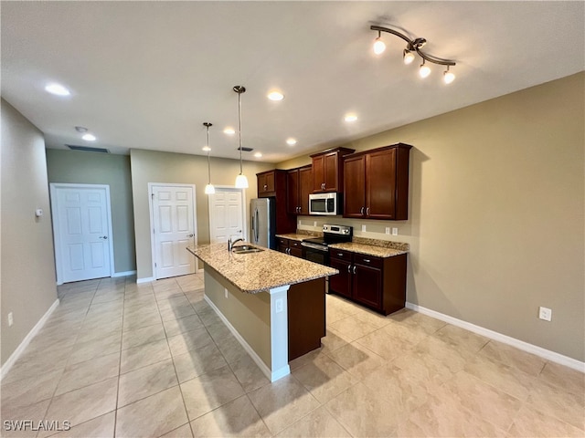 kitchen with light stone counters, stainless steel appliances, sink, pendant lighting, and a center island with sink