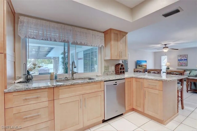 kitchen featuring light brown cabinetry, kitchen peninsula, sink, light tile patterned floors, and stainless steel dishwasher