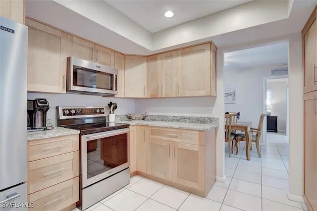 kitchen featuring light stone countertops, appliances with stainless steel finishes, light tile patterned floors, and light brown cabinets