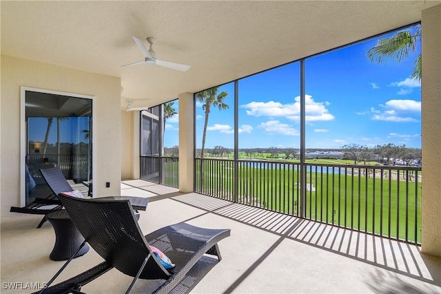 sunroom / solarium featuring a water view and ceiling fan