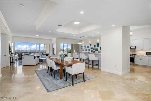 dining space with a raised ceiling