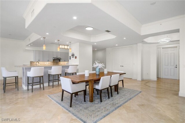 dining space featuring a raised ceiling, ornamental molding, and sink