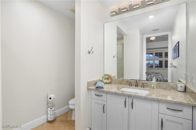 ensuite bathroom with vanity, connected bathroom, toilet, and baseboards