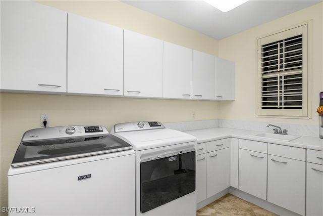 clothes washing area featuring separate washer and dryer, sink, light tile patterned floors, and cabinets