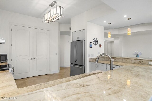 kitchen featuring light stone countertops, appliances with stainless steel finishes, and decorative light fixtures