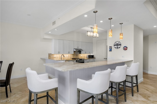 kitchen with white cabinets, a kitchen breakfast bar, ornamental molding, decorative light fixtures, and kitchen peninsula