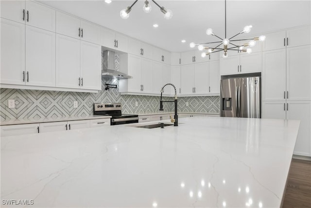 kitchen featuring wall chimney exhaust hood, light stone counters, sink, and appliances with stainless steel finishes