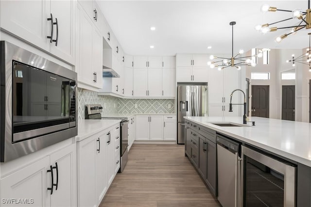 kitchen featuring white cabinetry, sink, stainless steel appliances, an inviting chandelier, and wine cooler