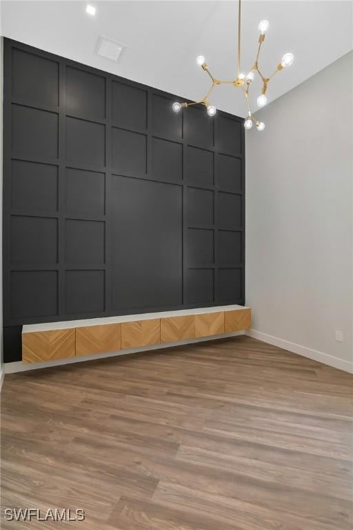 unfurnished room featuring a chandelier and light hardwood / wood-style flooring