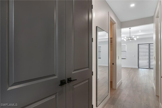 hall featuring light hardwood / wood-style floors and a chandelier