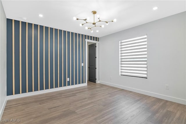 unfurnished room with hardwood / wood-style floors and an inviting chandelier