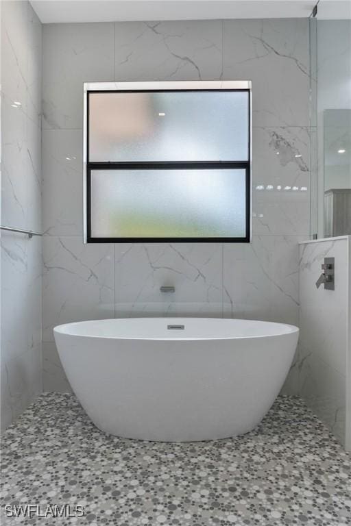 bathroom featuring plenty of natural light, tile walls, and a washtub