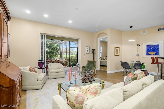 living area featuring baseboards, visible vents, arched walkways, and recessed lighting