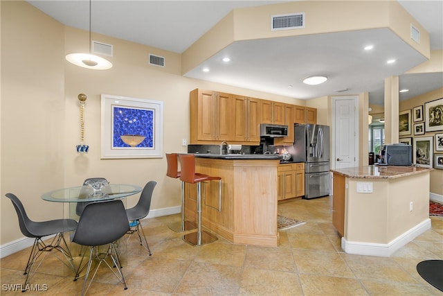 kitchen with appliances with stainless steel finishes, a breakfast bar area, and visible vents