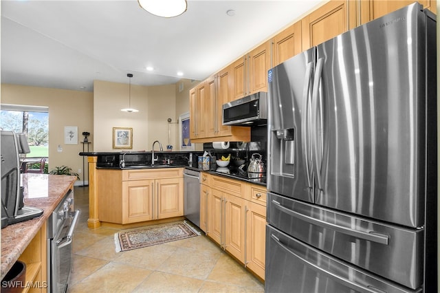 kitchen with appliances with stainless steel finishes, dark stone countertops, hanging light fixtures, a peninsula, and a sink