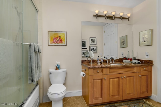 bathroom featuring bath / shower combo with glass door, baseboards, toilet, tile patterned flooring, and vanity