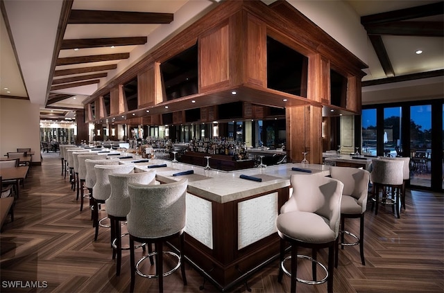 bar with wet bar, beamed ceiling, and a high ceiling