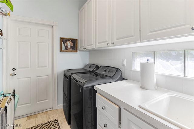 washroom featuring sink, washing machine and dryer, and cabinets