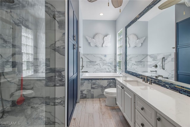 full bathroom featuring vanity, toilet, wood-type flooring, and shower with separate bathtub