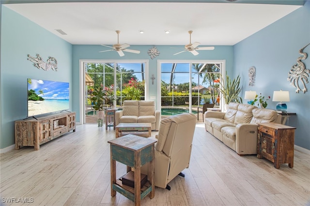 living room with light hardwood / wood-style flooring, ceiling fan, and a wealth of natural light