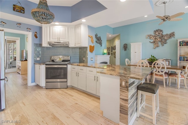 kitchen featuring kitchen peninsula, white cabinets, light stone counters, light hardwood / wood-style flooring, and stainless steel appliances