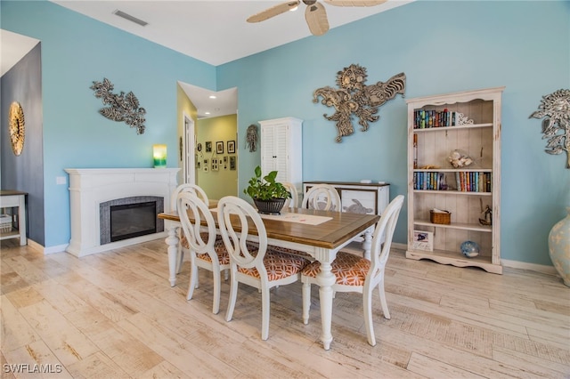 dining area featuring a high end fireplace, light wood-type flooring, and ceiling fan