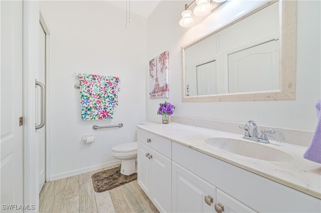 bathroom with toilet, hardwood / wood-style flooring, and vanity