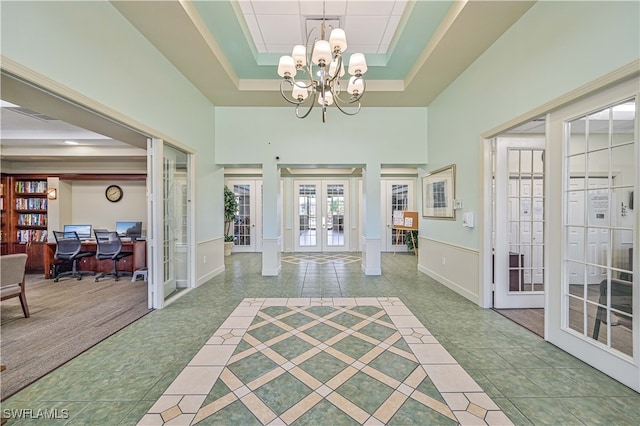 entrance foyer featuring french doors, a high ceiling, a notable chandelier, light colored carpet, and a raised ceiling