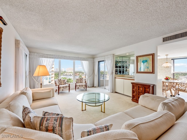 living room with a textured ceiling, sink, and light colored carpet