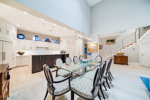 dining area featuring light hardwood / wood-style floors, a towering ceiling, and sink