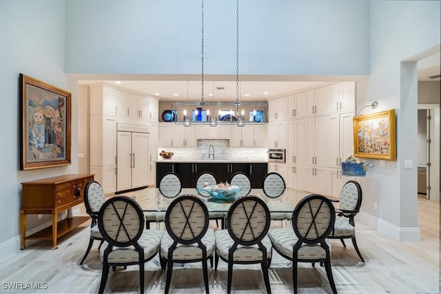 interior space with an inviting chandelier, light hardwood / wood-style flooring, sink, and a high ceiling