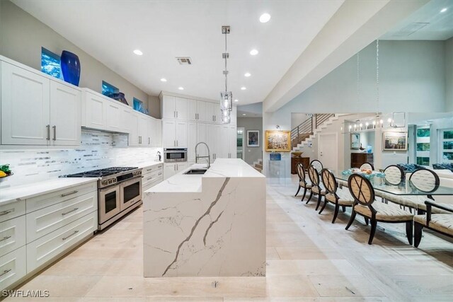 kitchen with a large island, light stone counters, stainless steel appliances, and pendant lighting