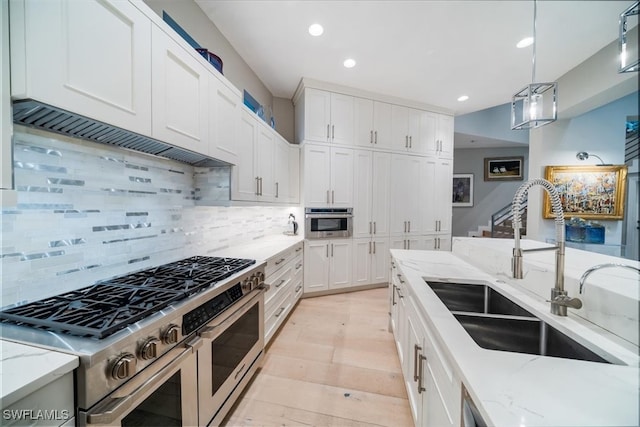 kitchen featuring decorative backsplash, stainless steel appliances, sink, pendant lighting, and white cabinetry