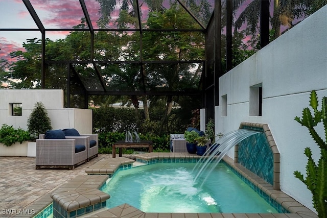 pool at dusk with a patio, a jacuzzi, a lanai, and pool water feature