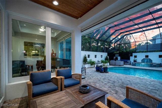 view of pool with a patio area, glass enclosure, and a jacuzzi