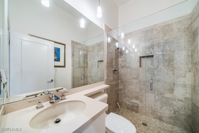 bathroom featuring toilet, vanity, and a shower with door