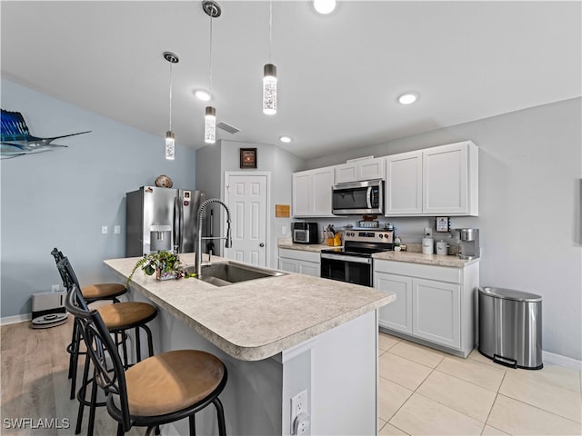 kitchen with pendant lighting, sink, white cabinetry, stainless steel appliances, and a center island with sink