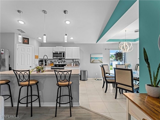 917 NW 13th Ave, Cape Coral, FL 33993 - kitchen featuring a notable chandelier, a breakfast bar area, hanging light fixtures, white cabinets, and appliances with stainless steel finishes