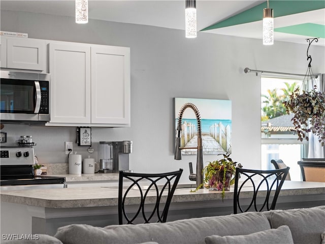 kitchen featuring a healthy amount of sunlight, electric range, decorative light fixtures, and white cabinets