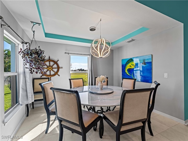 dining area featuring a chandelier, a raised ceiling, and light tile patterned floors