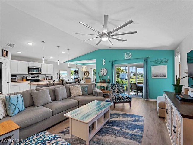 living room with ceiling fan, lofted ceiling, and light hardwood / wood-style flooring