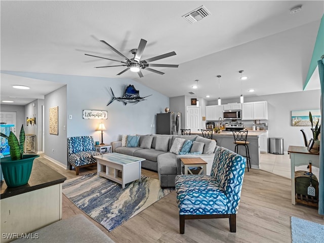 living room featuring lofted ceiling, ceiling fan, and light hardwood / wood-style flooring