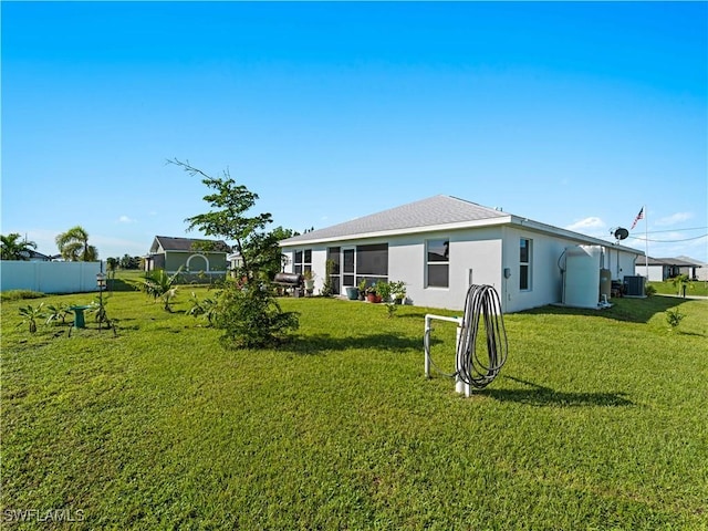 back of house with cooling unit and a lawn